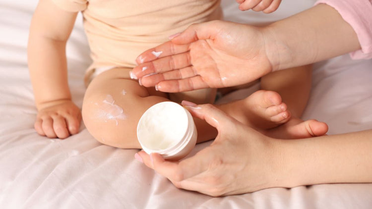 Mother applying baby moisturiser to a newborn as part of a gentle skincare routine