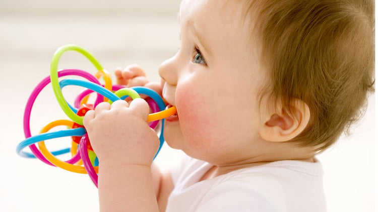Baby chewing a teething ring to soothe sore gums