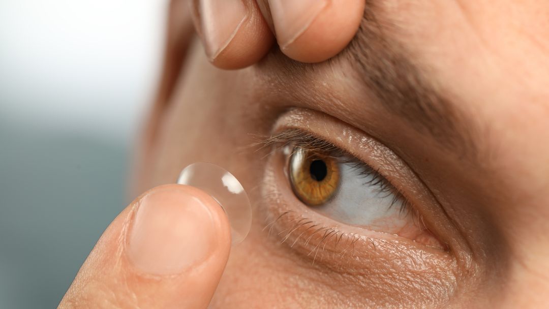 Person inserting a contact lens with clean hands as part of a daily lens care routine