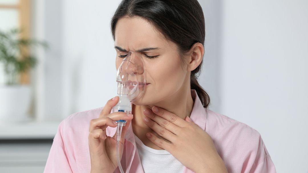 Person using a nebuliser mask for asthma or COPD respiratory treatment at home.