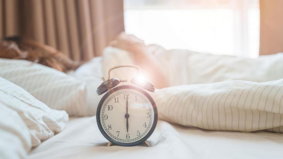Autumn clock change and sleep schedule with an alarm clock in a cosy bedroom