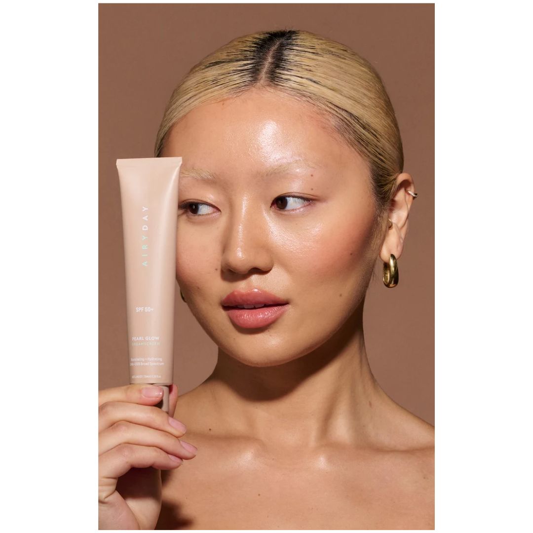 Airyday Pearl Glow SPF50+ Dreamscreen - woman holding up the product next to her face on a pink background