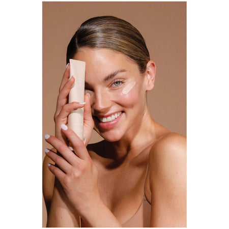 Airyday Pretty in Zinc SPF50+ Dreamscreen being held up by a woman with a smear of the lotion on her cheek
