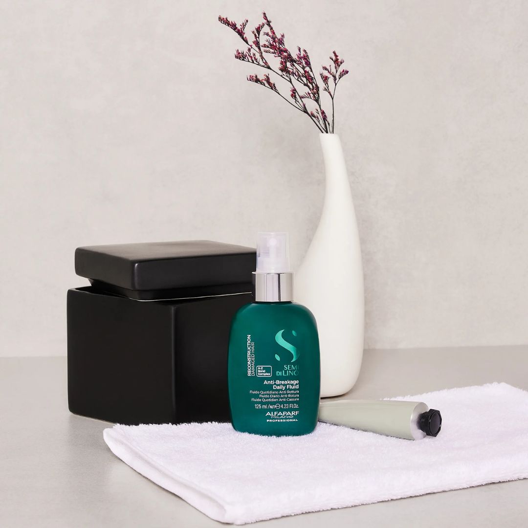 Cosmetic products including a green bottle, black container, and white vase on a light surface.