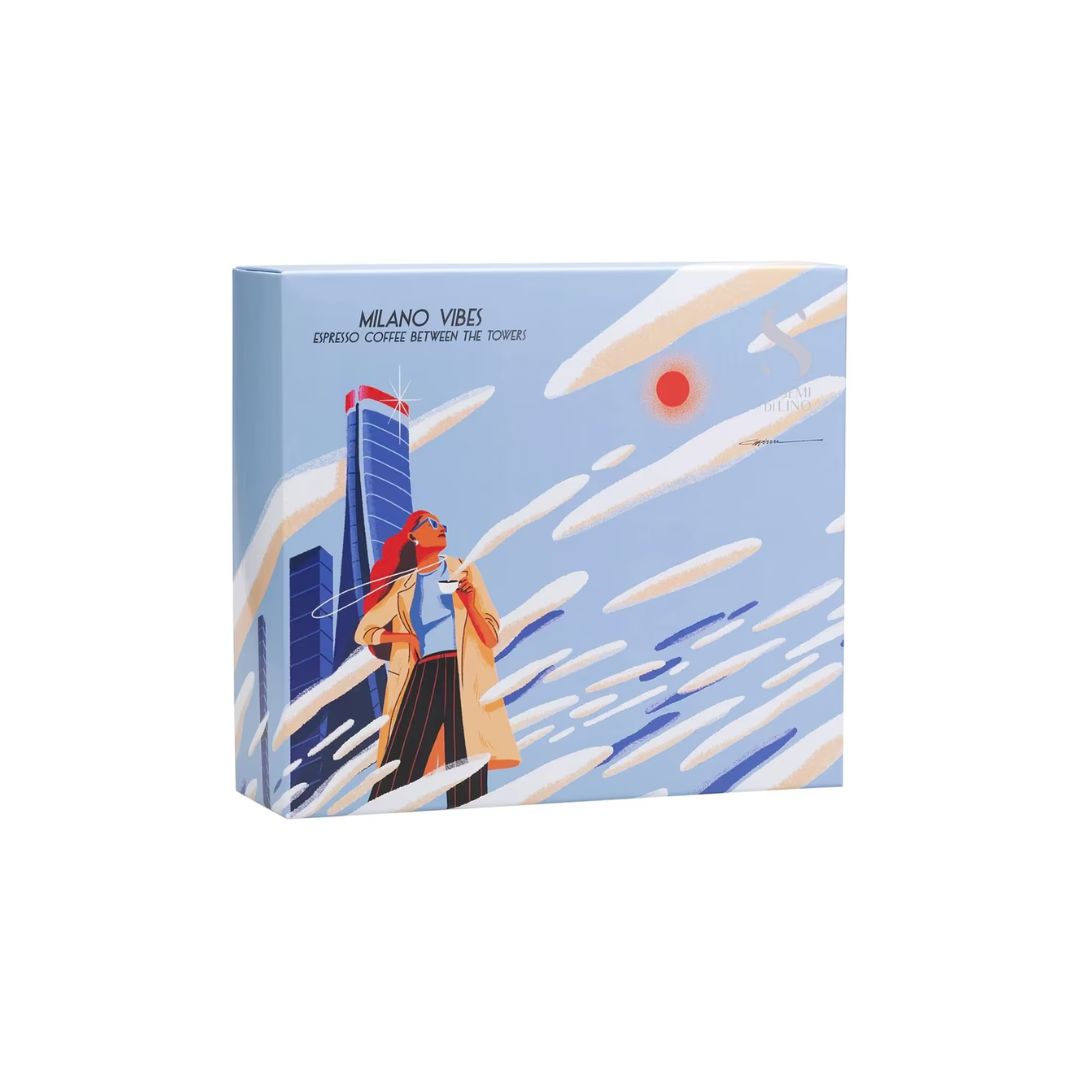 A square product box for Alfaparf Milano Semi Di Lino Density Gift Set on a white background, featuring a stylized illustration of a woman in a beige coat and red headscarf standing in front of a blue skyscraper against a light blue sky with white clouds and a red sun.
