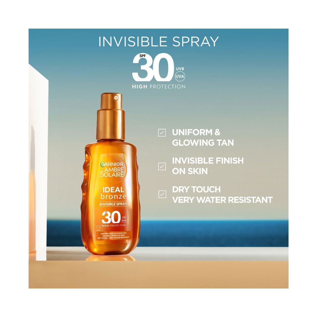 Garnier Ambre Solaire Ideal Bronze Invisible Spray bottle on a beachfront with product benefits to the right