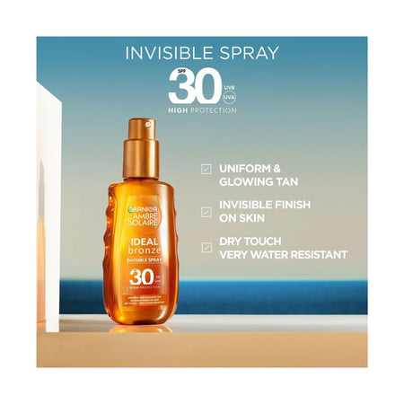 Garnier Ambre Solaire Ideal Bronze Invisible Spray bottle on a beachfront with product benefits to the right