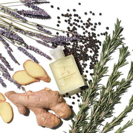 A frosted glass bottle of Aromatherapy London lavender body wash, styled in a flat lay with lavender sprigs, ginger roots, black peppercorns, and rosemary on a white background.
