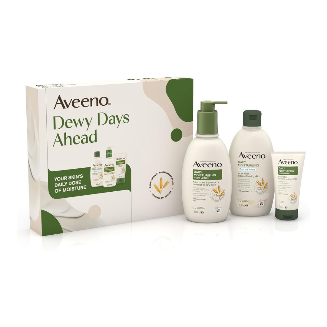 Aveeno Dewy Days Ahead skincare gift set featuring a white and green box alongside three bottles and a tube of moisturizing and body care products on a white background.