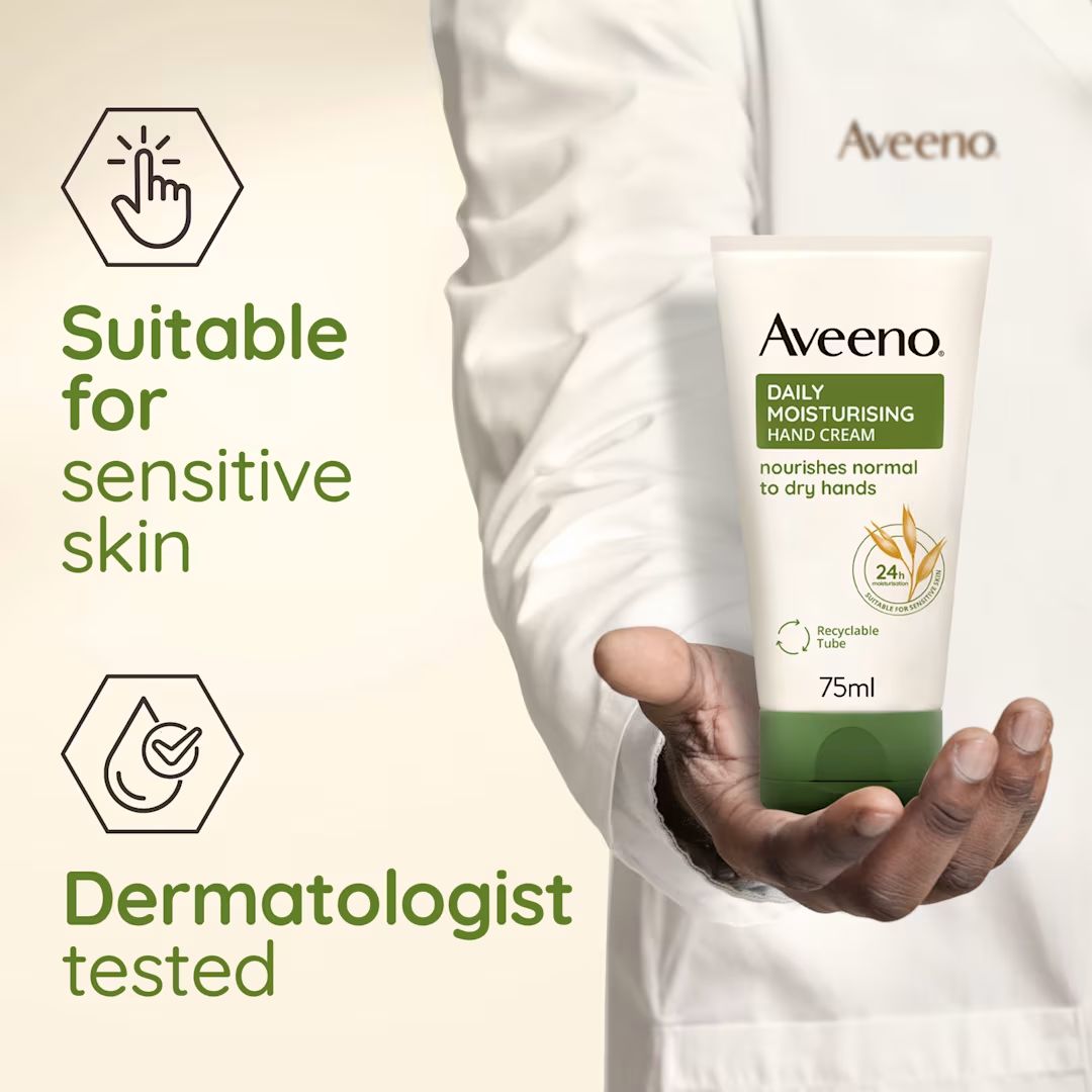 Aveeno Daily Moisturising Hand Cream 75ml tube held in a person's hand wearing a white lab coat, with marketing text on the left reading 'Suitable for sensitive skin' and 'Dermatologist tested'.
