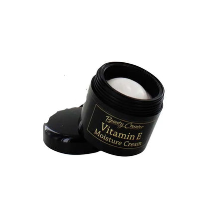A small black cosmetic jar labeled 'Beauty Couter Vitamin E Moisture Cream' with its lid placed beside it on a plain white background.