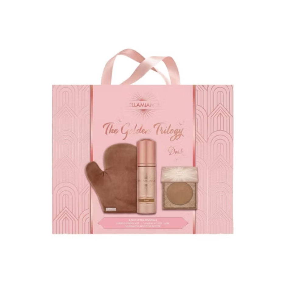 Ellamaire The Golden Trilogy Dust makeup set in a pink gift bag with ribbon handles, showing a brown mitt, a pink-toned bottle, and a square compact.