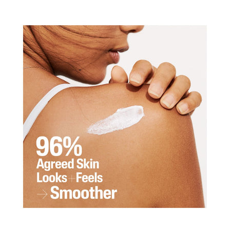 Close-up of a woman's shoulder and side profile with a smear of white sunscreen cream on her skin and large text reading '96% Agreed Skin Looks + Feels Smoother' on a light background.