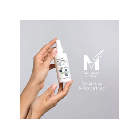 A hand holding a white bottle of Menopause Skin Purifier against a light gray background, with text indicating MTick certification and a Menopause Friendly badge.
