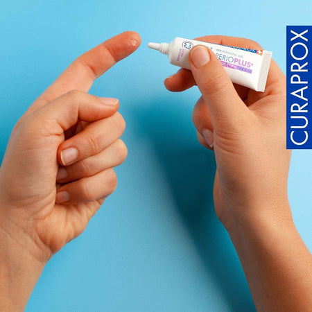 Person holding a tube of Curaprox dental gel against a blue background