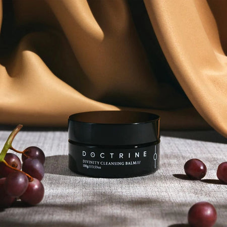 Black jar labeled 'Doctrine' with grapes on a textured surface