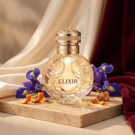 Elie Saab Elixir Eau de Parfum 50ml on a marble slate with flowers and orange peel