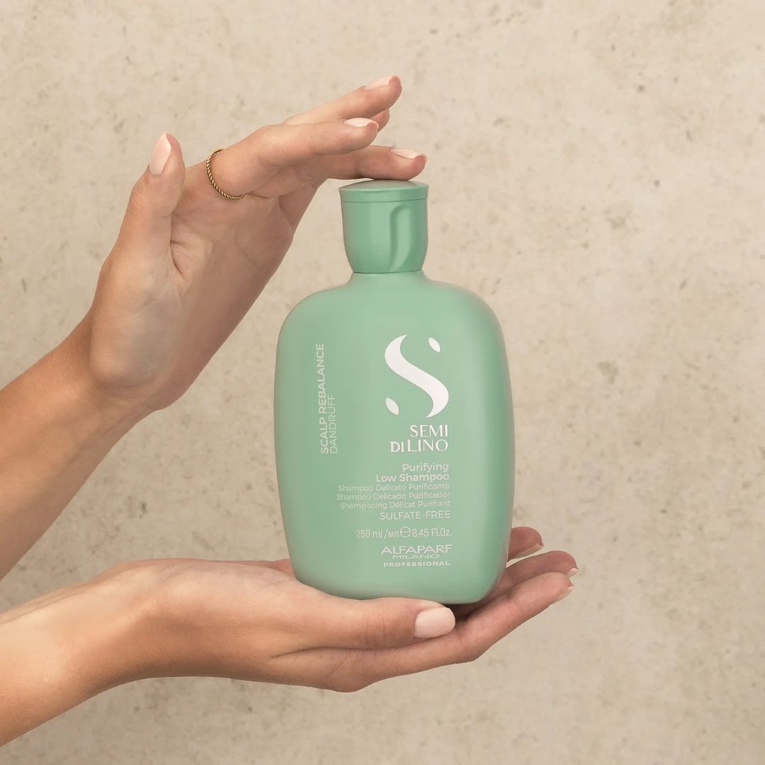 Person holding a green bottle of Sergio De Lino shampoo against a beige background