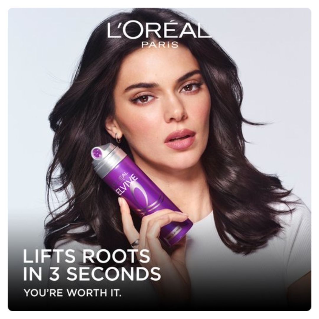 L'Oréal Paris Elvive hair lift canister held by a model with long dark brown hair, set against a light gray background with promotional text.