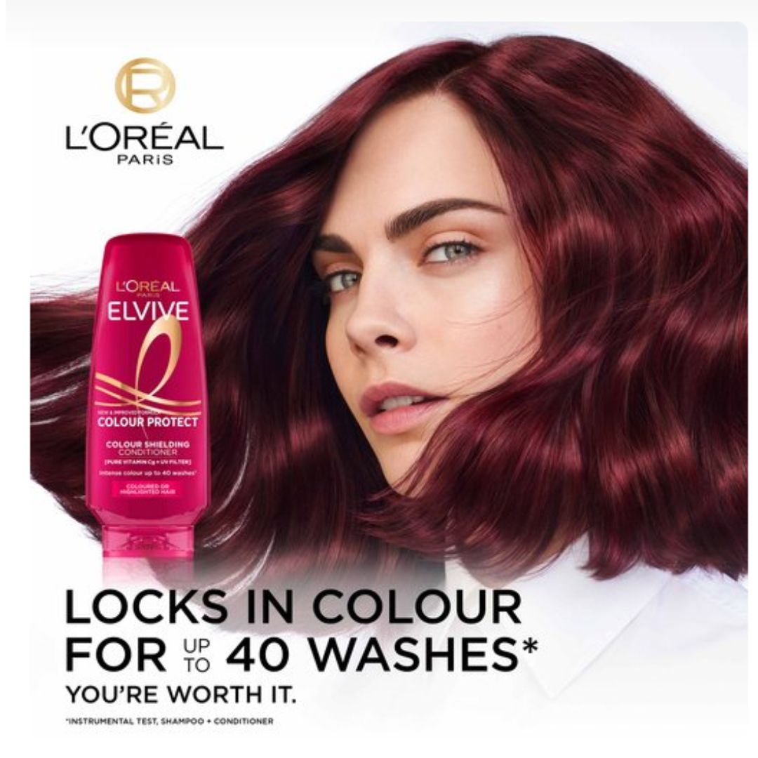 L'Oréal Paris Elvive Colour Protect shampoo bottle shown next to a model with long, wavy burgundy hair on a white background.