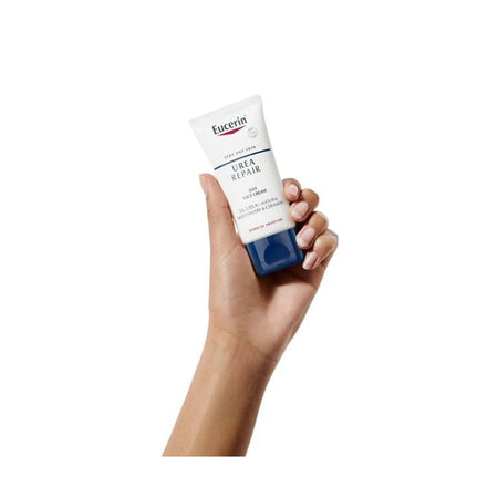 A hand holding a squeeze tube of Eucerin Urea Repair B5 Cream against a solid white background.