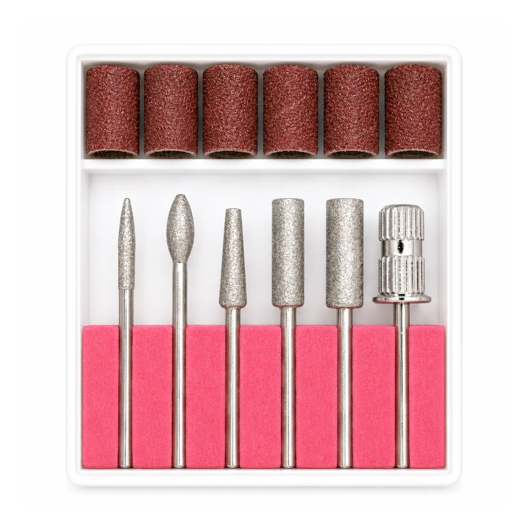 A 7-piece nail drill bit set with various metal diamond and abrasive bits, shown in a white plastic organizer tray with six brown sanding rolls on top and pink foam grips underneath.