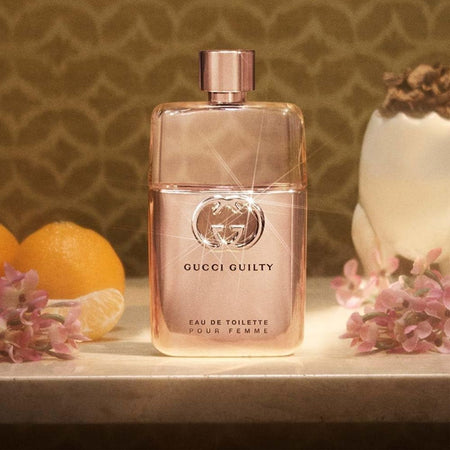 Gucci Guilty Pour Femme Eau de Toilette 50ml on a marble countertop with product ingredients