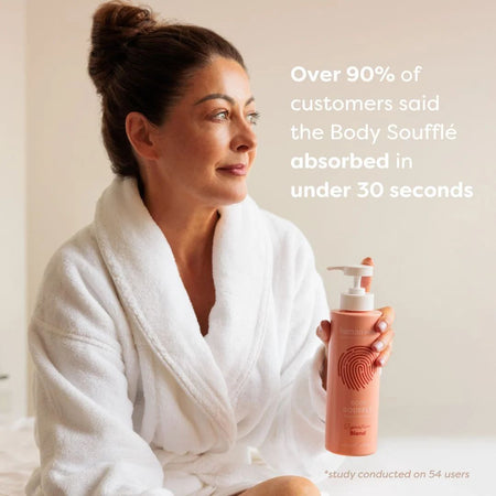 Human+Kind Signature Blend Body Soufflé 500ml being held by a woman in a bath robe