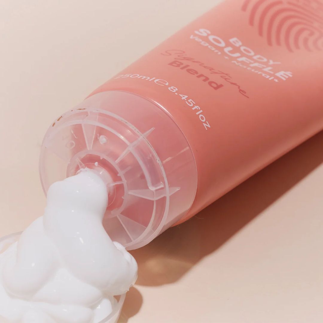Human+Kind Signature Blend Body Soufflé being squeezed on a pink background