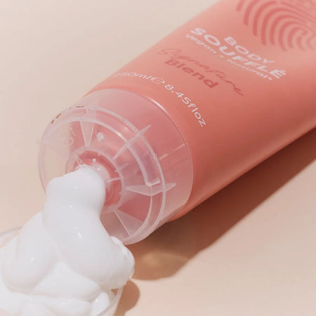 Human+Kind Signature Blend Body Soufflé being squeezed on a pink background