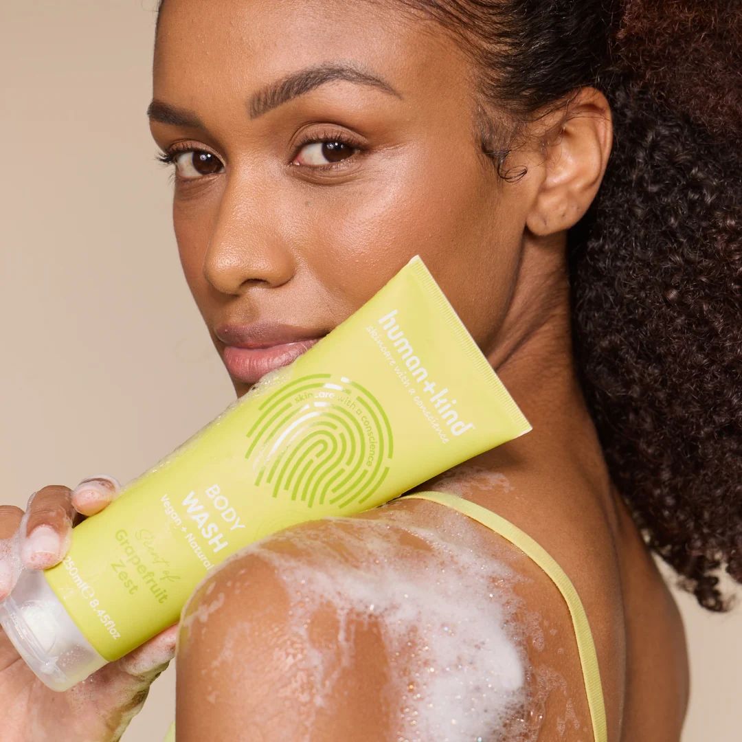 Human+Kind Grapefruit Zest Body Wash 250ml being held by a woman on her shoulder