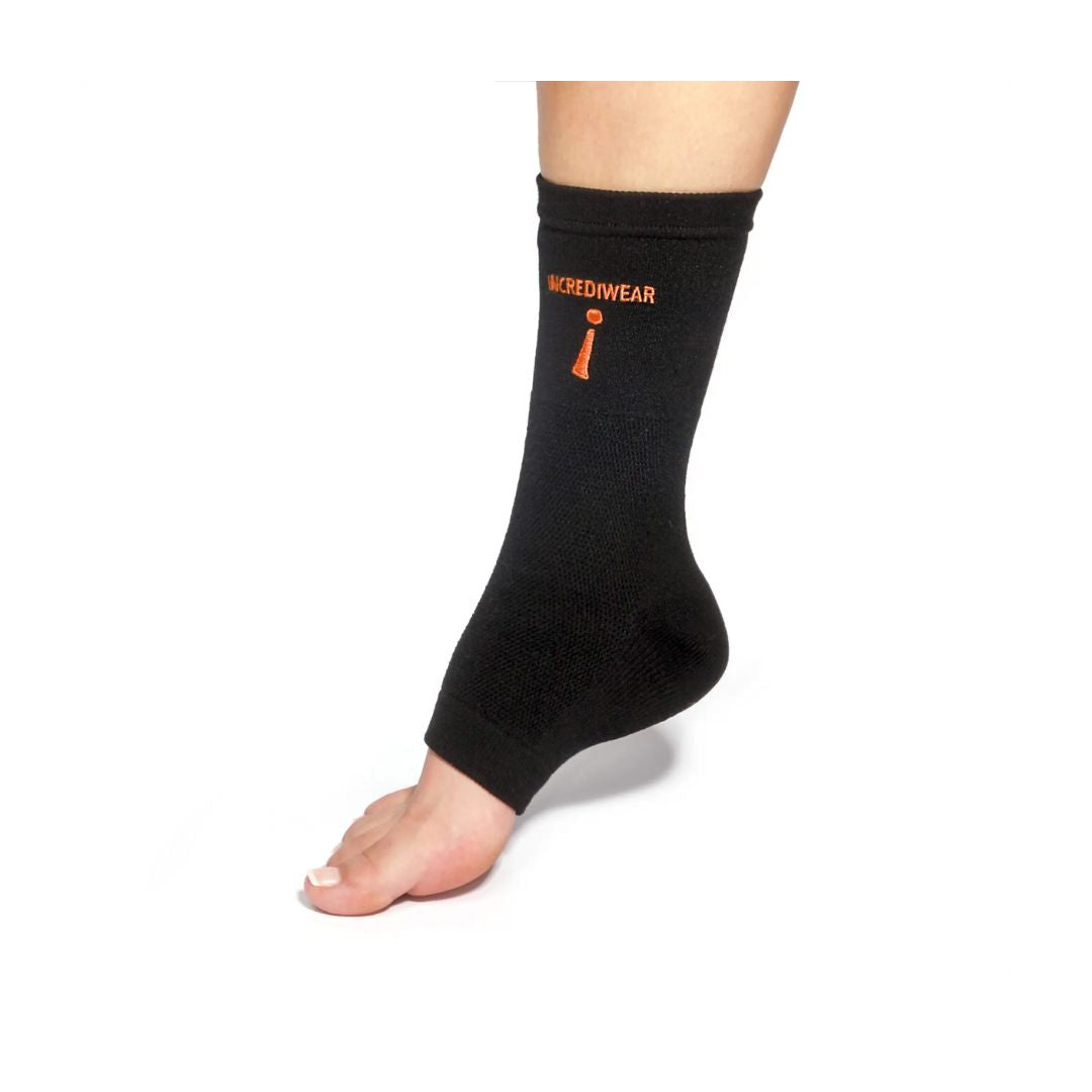 A black ankle support sleeve worn on a person's foot, featuring an orange logo and graphic on the side, set against a plain white background.
