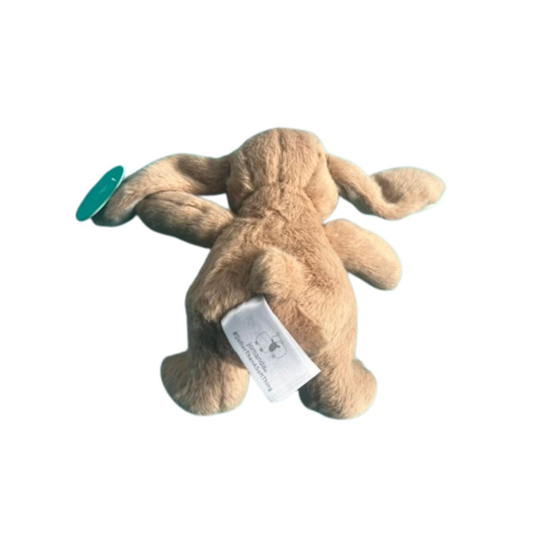A light brown plush stuffed animal toy, shown from the back, featuring floppy ears, a white product tag, and a small teal circular accent on the left side, isolated on a white background.