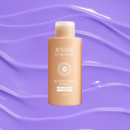 A bottle of Juvare Complex Blonde Toning Shampoo centered against a purple background with glossy liquid swirls. The bottle is a warm light beige/peach color with white text and a white cap.