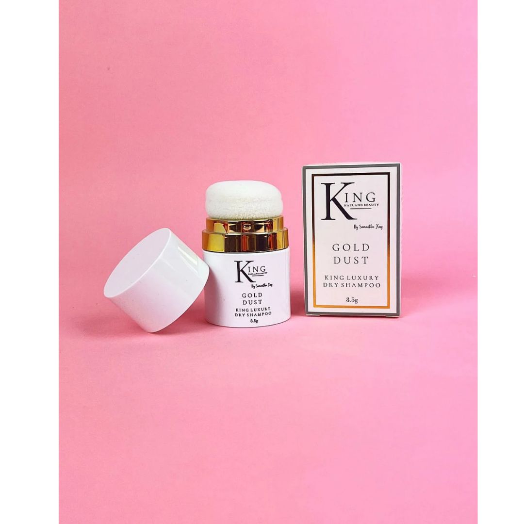 King of Beauty Gold Dust Daily Shampoo jar with its cap off next to its retail box, set against a solid pink background.