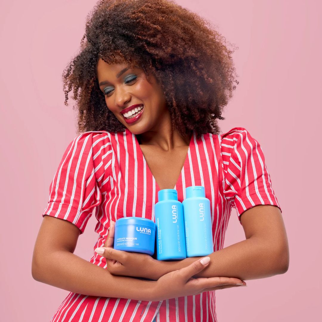 Luna The Hydrate Edit Gift Set contents being held by a woman on a pink background
