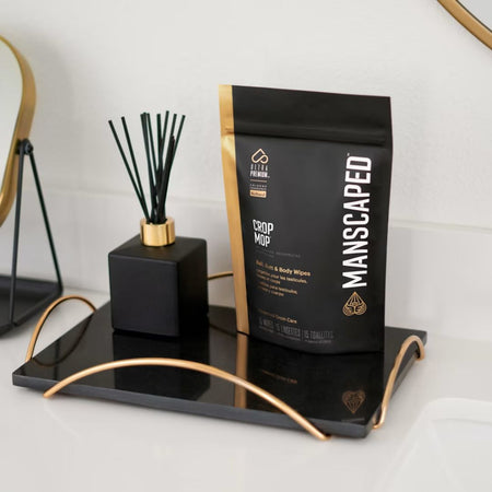 Manscaped product packaging on a black tray with a decorative item.