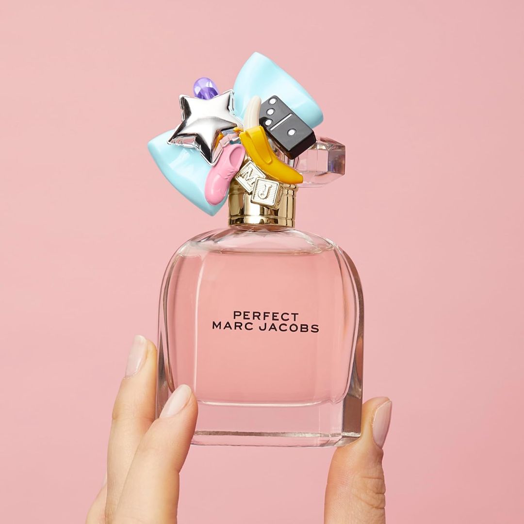 Marc Jacobs Perfect Eau de Parfum 50ml being held in someones hand on a pink background