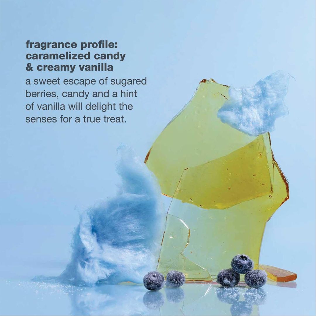 A stylized fragrance concept shot on a light blue background showing translucent yellow and green wax-like shards, fluffy white cotton-like texture, and a few blueberries. Text on the left reads: 'fragrance profile: caramelized candy & creamy vanilla a sweet escape of sugared berries, candy and a hint of vanilla will delight the senses for a true treat.