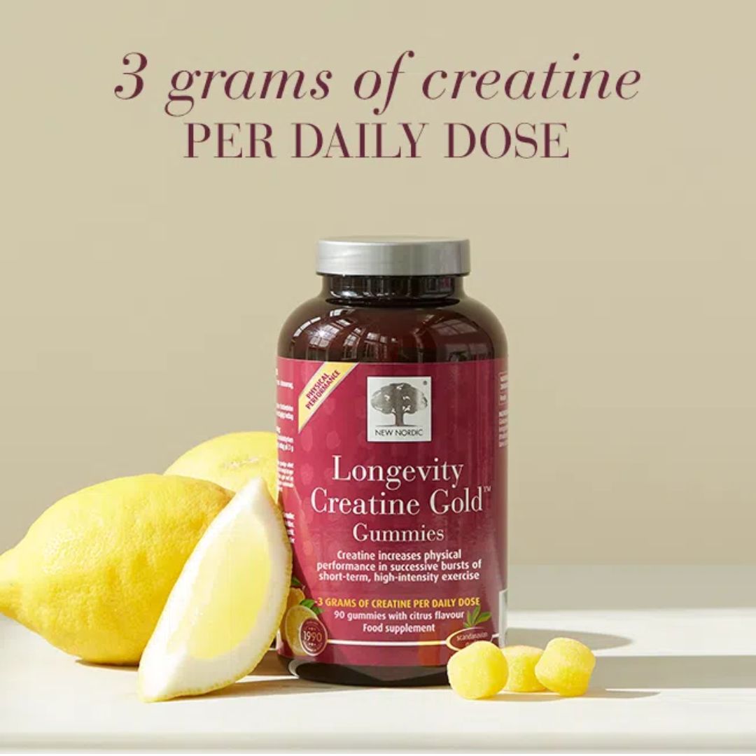A bottle of longevity creatine gold gummies displayed on a white surface with lemons and a few yellow gummies, under the text '3 grams of creatine PER DAILY DOSE' on a beige background.
