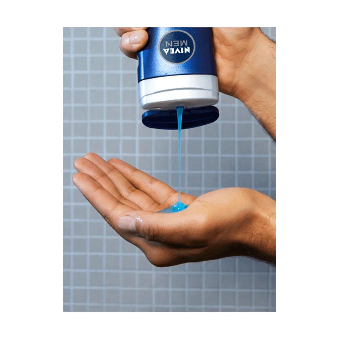 NIVEA MEN Sport 3-in-1 Shower Gel 500ml being poured into a mans hand in the shower on a grey tile background