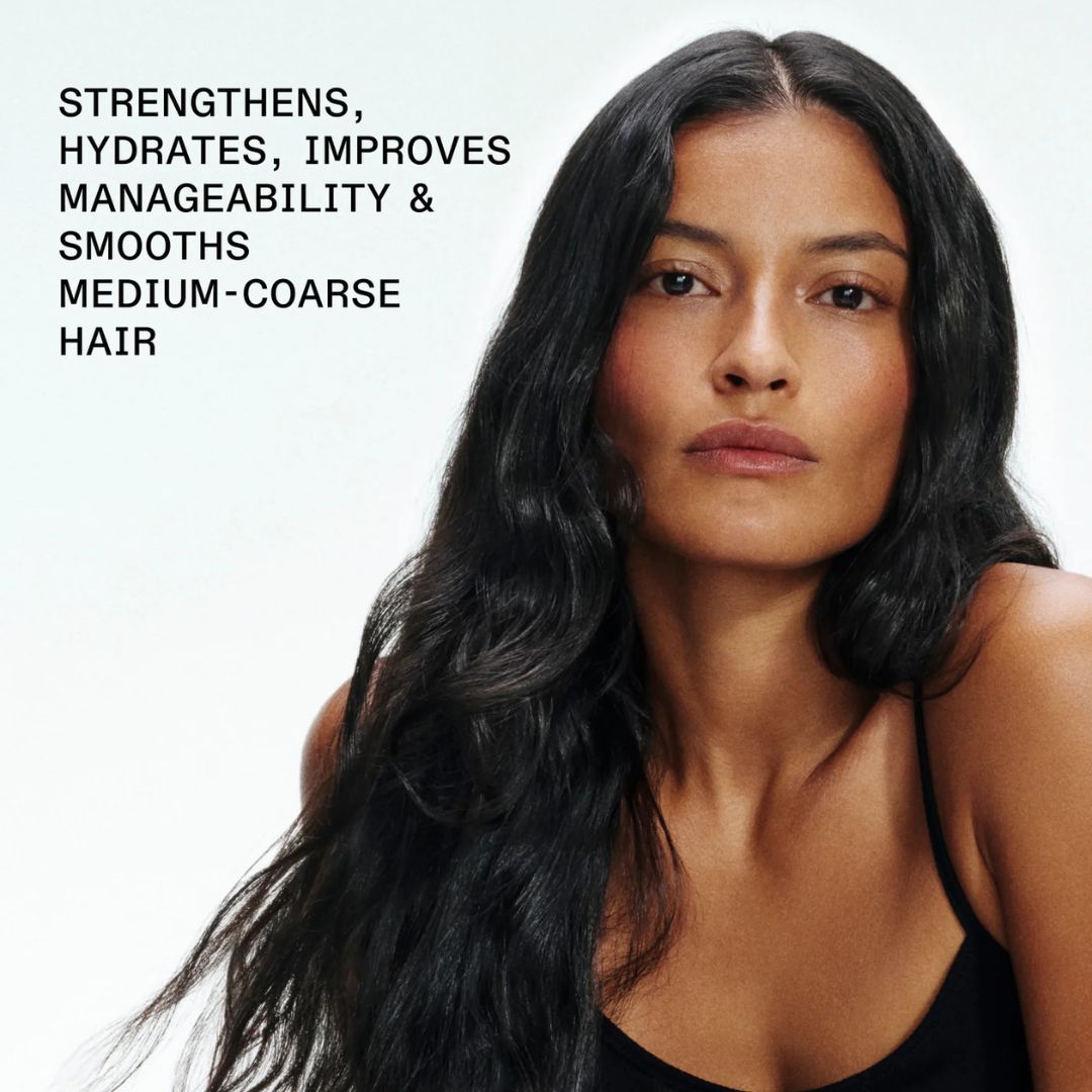 Olaplex No. 5 Bond Mainteance Conditioner - A woman with long, dark, wavy hair wearing a black top, shown against a light gray background with promotional text on the left that reads: 'STRENGTHENS, HYDRATES, IMPROVES MANAGEABILITY & SMOOTHS MEDIUM-COARSE HAIR'.