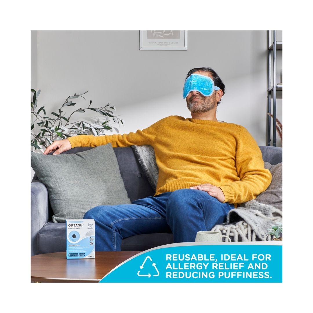 OPTASE Cooling Mask on a man's face who is seated on a sofa with rthe product packaging on a table in front
