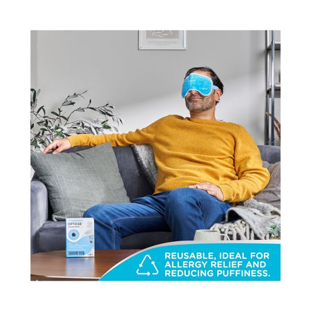 OPTASE Cooling Mask on a man's face who is seated on a sofa with rthe product packaging on a table in front