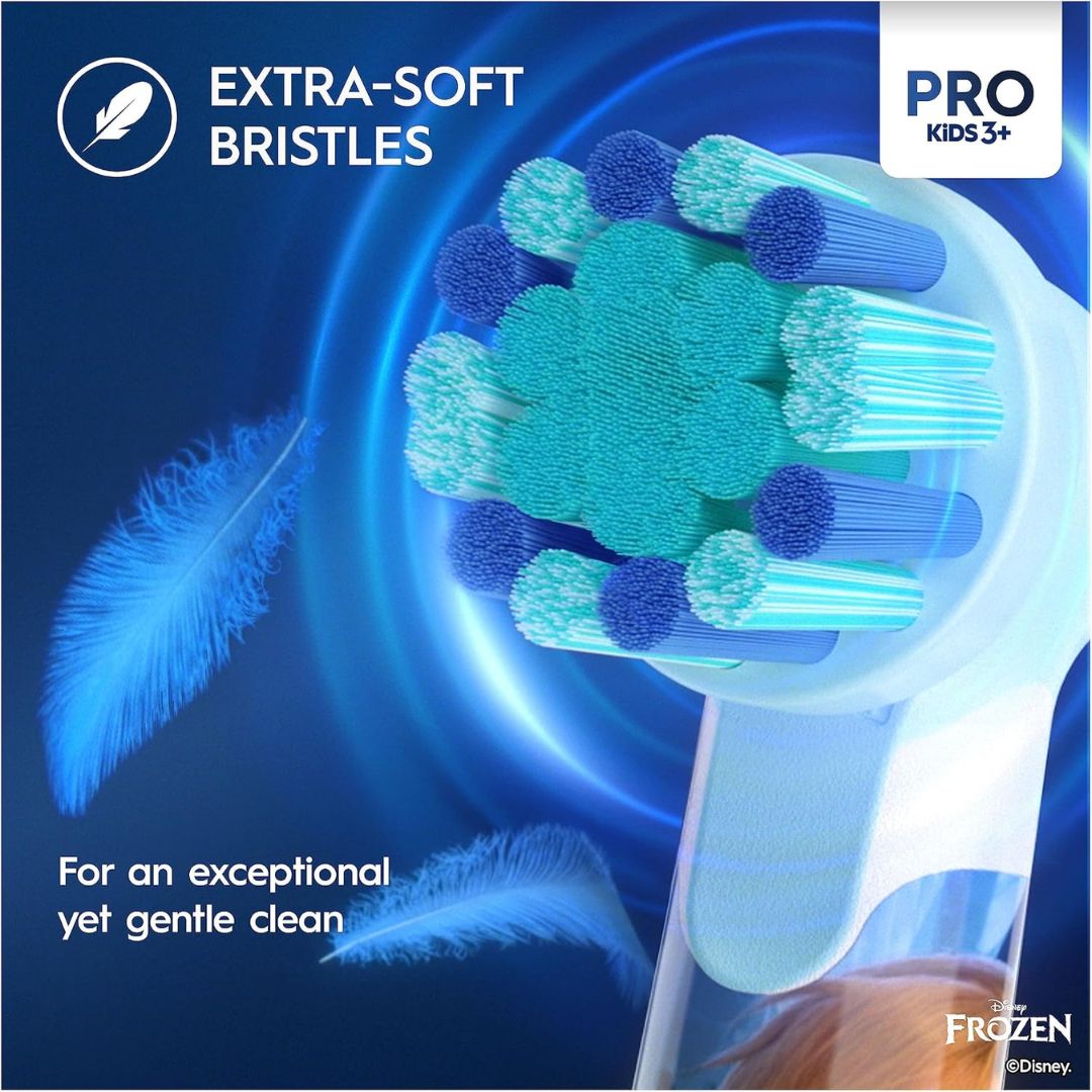 Extra-soft bristle baby toothbrush with a floral brush head, shown on a dark blue graphic background with feather illustrations and text reading 'EXTRA-SOFT BRISTLES' and 'PRO KIDS 5+'. Brand 'Frozen' with Disney copyright is visible in the lower right.