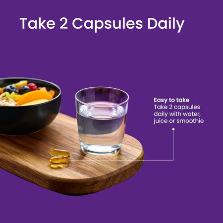 Glass of water, bowl of fruit, and capsules on a wooden board with purple background and text.