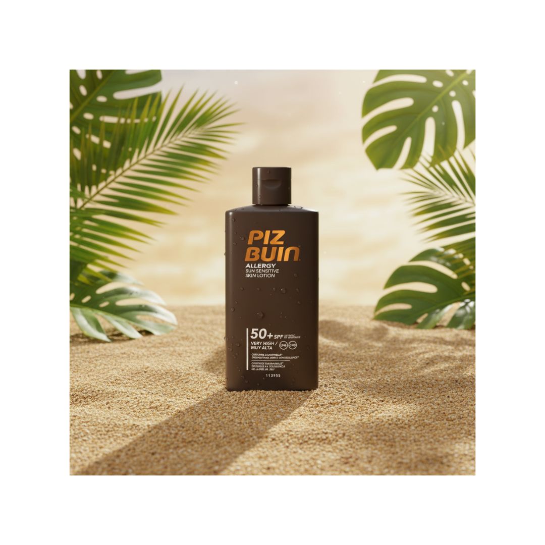 A dark brown bottle of Piz Pin Allergy & Sensitivity Sun Lotion SPF 50+ with orange lettering, set on a sandy beach background with tropical palm and monstera leaves.