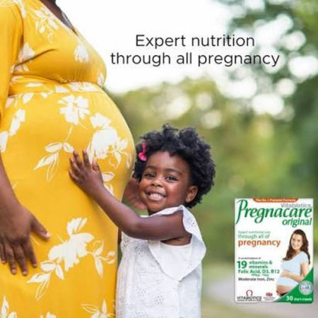 Pregnant woman in yellow dress with a child touching her belly, alongside a Pregnacare supplement box.