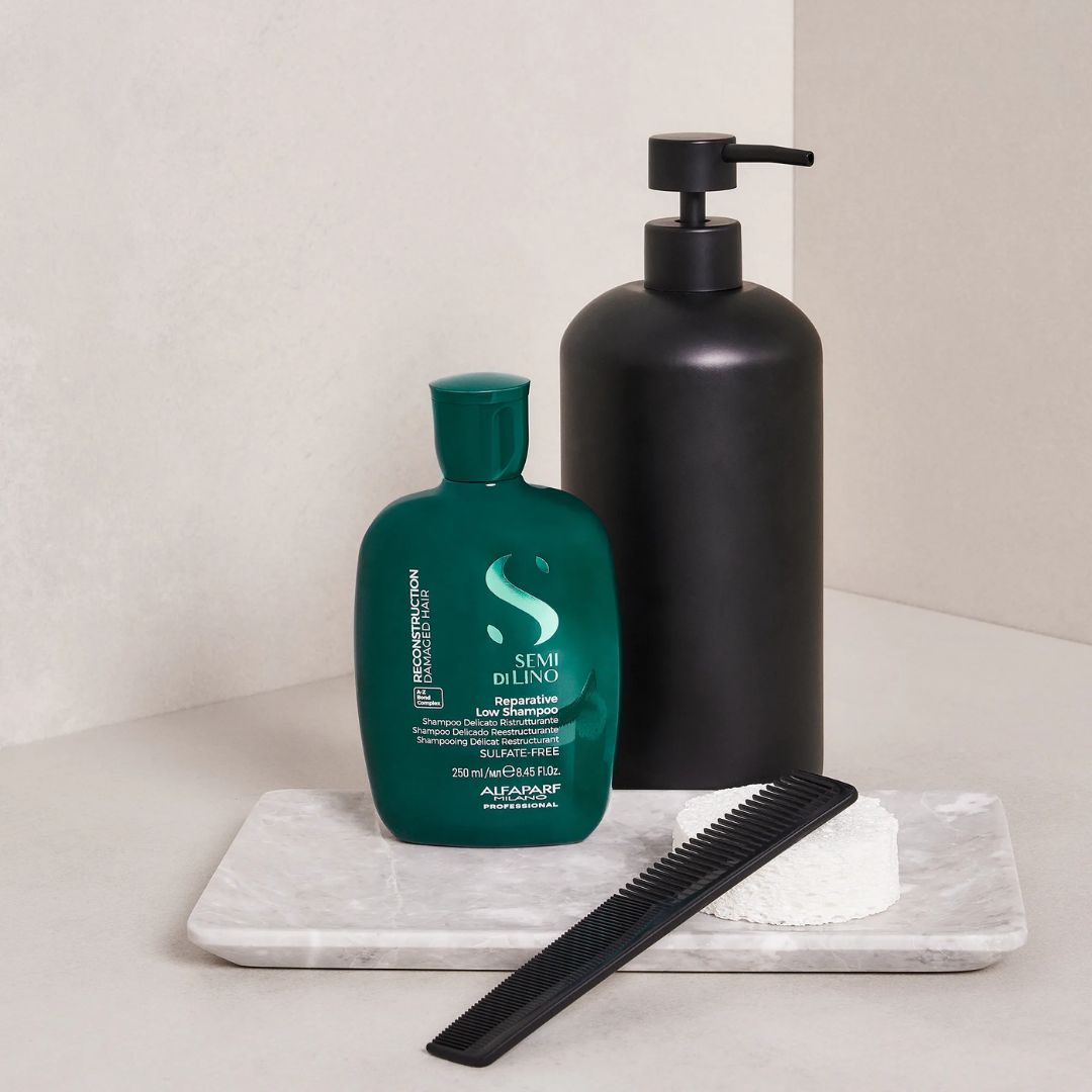 Two bottles of shampoo and a comb on a marble tray with a neutral background