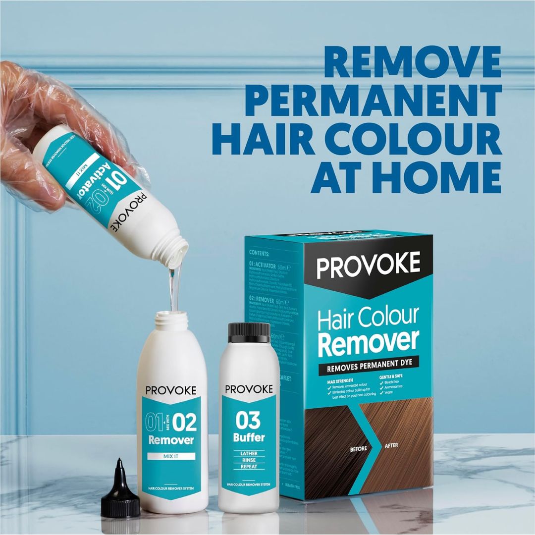 A hand wearing a clear plastic glove pours liquid from a Provoke hair color remover bottle into another bottle, with a third bottle standing beside it and the Provoke Hair Colour Remover box on a light blue background. Large text reads 'REMOVE PERMANENT HAIR COLOUR AT HOME'.